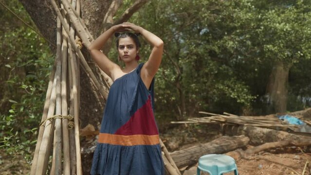 Indian fashion model posing in the forest of goa india while wearing a sustainable fashion dress in blue, red and orange in Slow Motion