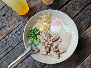 Pork porridge put eggs in a cup on brown wooden floor, top view