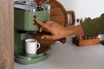 Young woman making coffee in kitchen, closeup
