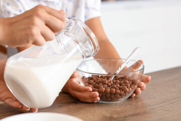 Happy mother with her little daughter having breakfast in kitchen, closeup