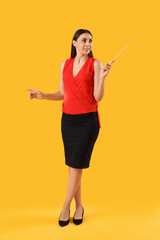 Young female teacher with pointer on yellow background