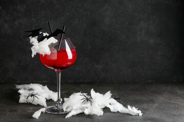 Glass of tasty Margarita cocktail and decorations for Halloween on black background