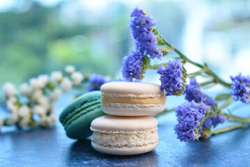 Obraz na płótnie Canvas Sweet macaroons and beautiful flowers on blue table