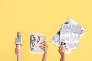 Female hands with microphone and newspapers on color background