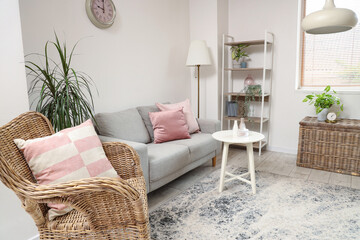 Fototapeta na wymiar Comfortable armchair, sofa, basket and table in living room
