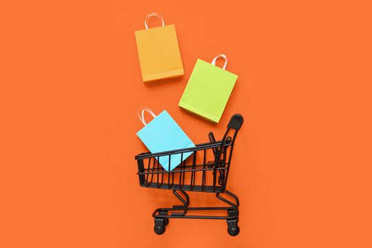 Small shopping cart and bags on orange background