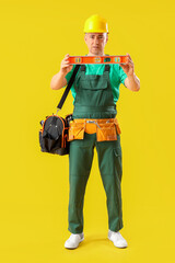 Mature worker with level on yellow background. Labor Day celebration