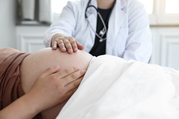 Fototapeta na wymiar 침대에 누워있는 임산부에 손을 얹은 의사