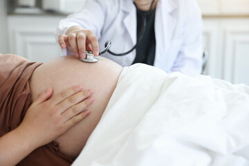 Obraz na płótnie Canvas 침대에 누워있는 임산부에 청진기를 대고있는 의사