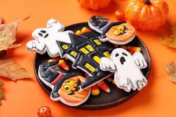Plate with different tasty cookies for Halloween celebration on orange background, closeup