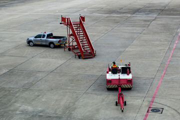 Airplane tow tractor at the airport apron near the terminal. Aircraft Towing Tractor.  A towing tractor belonging in air port is being operated by officer. Aerodrome tow tractor is driving at airport