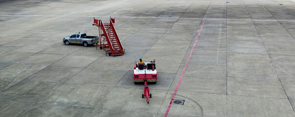 Airplane tow tractor at the airport apron near the terminal. Aircraft Towing Tractor.  A towing tractor belonging in air port is being operated by officer. Aerodrome tow tractor is driving at airport