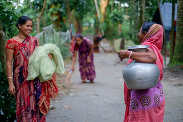 Bangladeshi village women are working and gossiping with each other in their own yard , women...