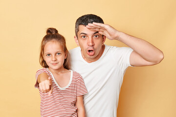 Shocked astonished man looking far with hand near forehead and little kid girl pointing to camera...