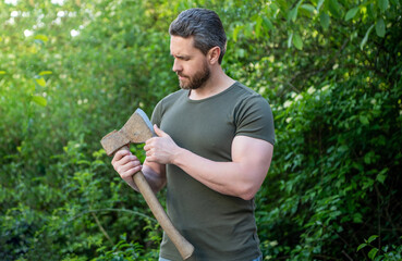 man holding ax. man with ax wearing shirt. man with ax outdoor. photo of man with ax