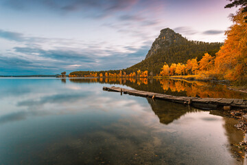 Old wooden pier on the mountain lake at sunset time. Beautiful autumn cloudscape on prolonged...