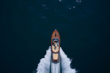 Top view of a wooden powerful motor boat. Luxurious wooden boat fast movement on dark water.Man and...