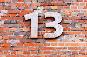 Metal number 13 on brick wall