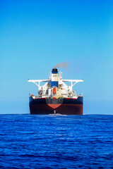 Huge red cargo ship cruising on a very calm ocean 
