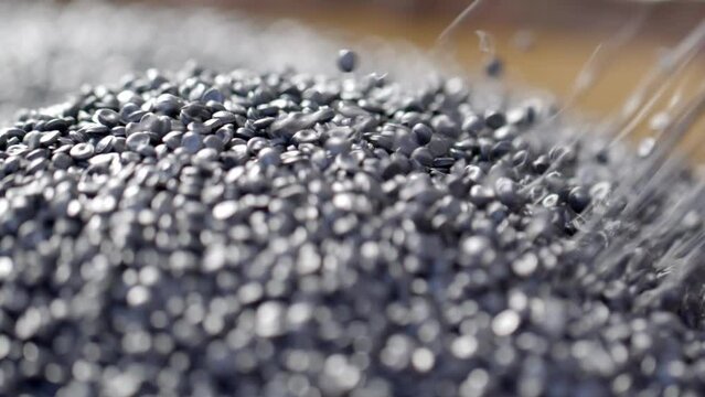 Hands With Protective Glove Lift Black Polymer Granules in a Garbage Recycling Plant Close-Up Shot