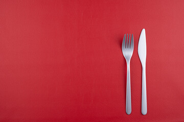 赤いレザーの上に置かれたナイフとフォーク - Powered by Adobe