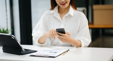 Businesswoman using mobile phone, tablet.Closeup on blurred background office.