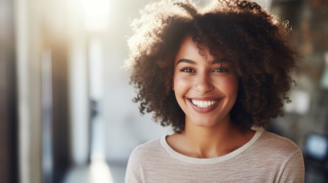 Smiling woman's portrait with afro hair, exuding happiness in a close-up shot