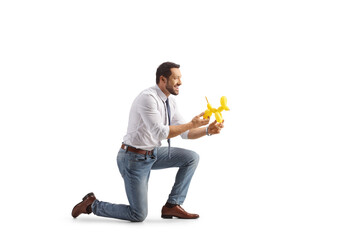 Profile shot of a man kneeling and holding a dog made from a balloon