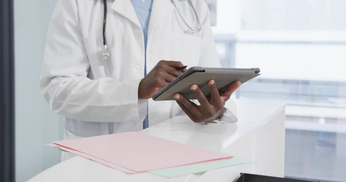 Midsection of african american male doctor using tablet in hospital, slow motion