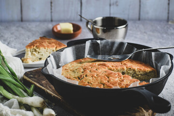 Onion bread made in a cast iron pan, a slice is cut and enjoyed with butter.