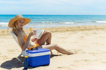 happy girl sits on the beach in a swimsuit reads a book and drinks a cocktail.beautiful seascape