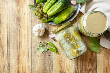 Healthy homemade fermented food. Salted pickled cucumbers with garlic, preserved canned in glass jar. Home economics, autumn harvest preservation. View from above. Copy space.