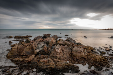 Clouds gather over a beach and rocks