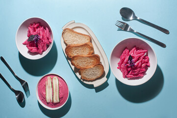 Delicious trendy pink beetroot pasta and hummus on minimalist blue background recipe copy space stylish flat lay
