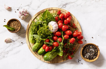 Fresh tomatoes, cucumbers and spices for healthy homemade fermented on a marble table. Home economics, autumn harvest preservation. View from above.