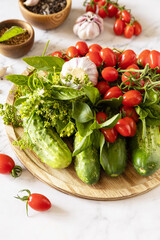 Home economics, autumn harvest preservation. Fresh tomatoes, cucumbers and spices for healthy homemade fermented on a marble table. Copy space.