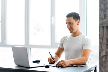 Fototapeta premium retoucher freelancer at work, a man with a laptop completes an order 