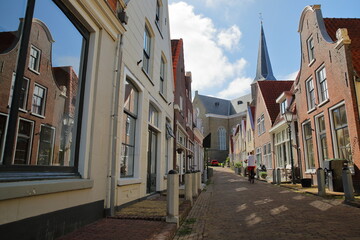 Grote Kerk church viewed from Grote Kerkstraat street in Harlingen, Friesland, Netherlands, with colorful historic buildings in the foreground