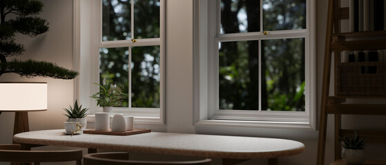 Copy space on a dining table by the window in a comfortable and minimalist room in the evening