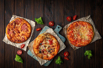 Three mini pizzas on brown boards. Bakery products. Fresh bakery.