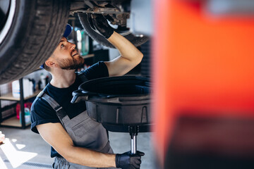 Car mechanic changing oil and oil filter