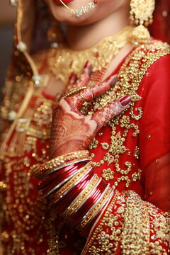 Bride Showing hands applied henna , decorative hands, bangles red dress mehndi, rings and jewelry , indian pakistani bride