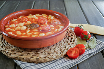 beans stewed with chorizo and blood sausage in a clay pot with tomato and bay leaves