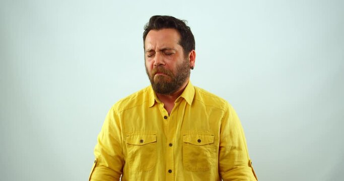 A middle-aged man is making a funny disgusted face for the camera. His nose is wrinkled and his mouth is turned up in a grimace. He appears to be disgusted by something.