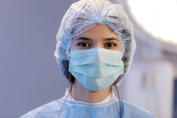 A very close up shot of a beautiful nurse with brown eyes and eyebrows wearing a medical mask and hairnet straying directly at the camera