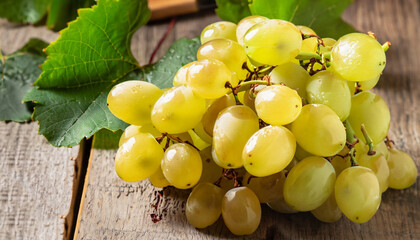 Sweet yellow grape with leaves on the rustic wooden table, selective focus