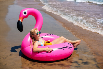 Child girl lies, relaxes on an inflatable flamingo ring on the beach. Sea, relaxation, vacation © Alena Vilgelm