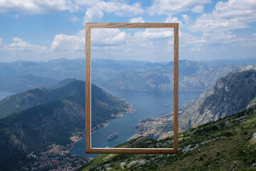 Wooden frame and beautiful bay between mountains under blue sky with clouds