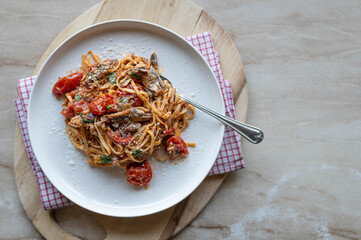 Mediterranean pasta dish with sardines, tomatoes, herbs and parmesan cheese on a plate