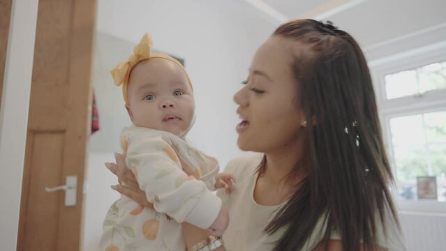 Smiling woman playing with baby daughter at home